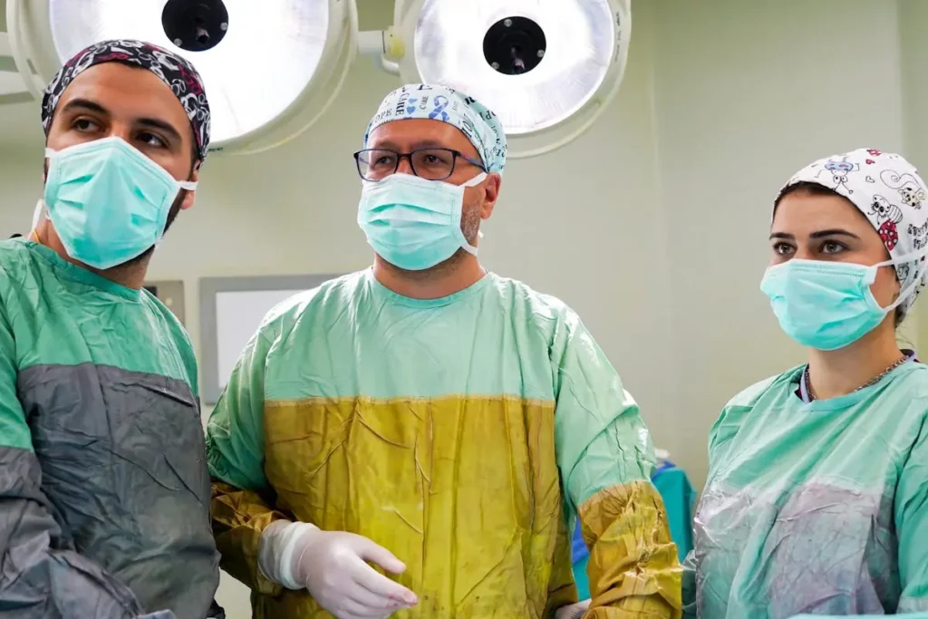 Three surgeons in scrubs and masks in operating room