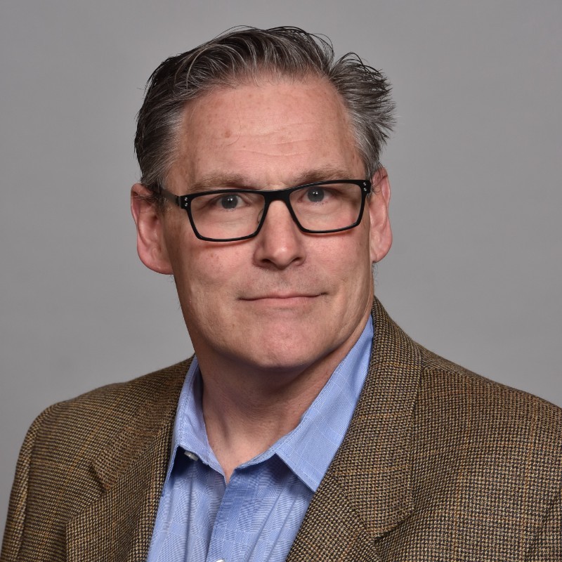 Mature man wearing glasses in tweed jacket and blue shirt
